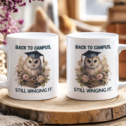 Two white mugs with an owl design and text on a wooden coaster.