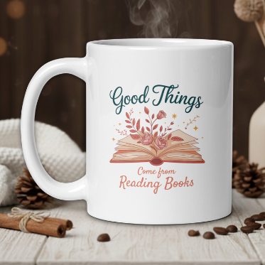 White mug with 'Good Things Come from Reading Books' design on a wooden table with coffee beans and a vase.