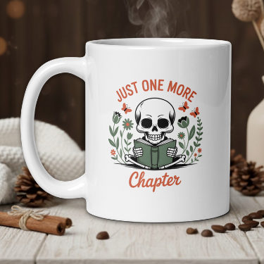 White mug with skull and book design, text 'Just One More Chapter', steam rising, on a wooden table with cozy background.