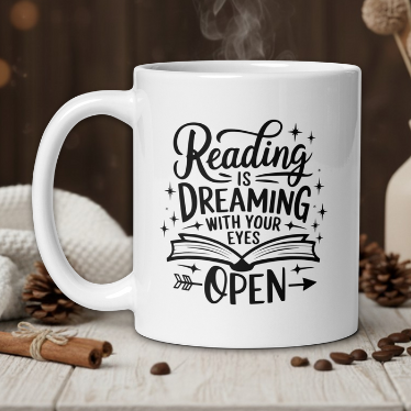White mug with 'Reading is Dreaming with Your Eyes Open' text on a wooden table with coffee beans and a vase.