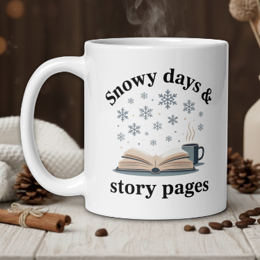 White mug with 'Snowy days & story pages' text on a wooden table with coffee beans and a vase.