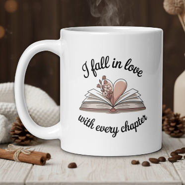 White mug with 'I fall in love with every chapter' design on a wooden table with coffee beans and a vase in the background.
