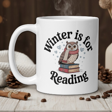 White mug with owl design and 'Winter is for Reading' text on a wooden table with cozy background.
