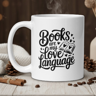 White mug with 'Books are my love language' text on a wooden table with coffee beans and a vase in the background.
