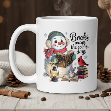 White mug with a snowman design and 'Books warm the coldest days' text, placed on a wooden surface with decorative items.