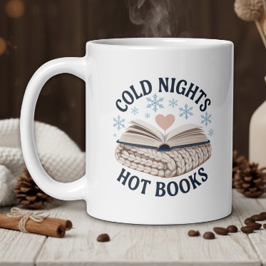 White mug with 'Cold Nights Hot Books' design on a wooden table with coffee beans and a vase in the background.