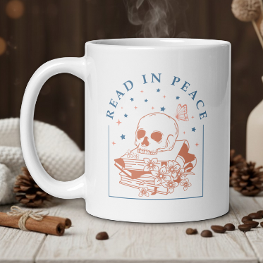 White mug with skull and books design, text 'Read in Peace', steam rising, on a wooden table.