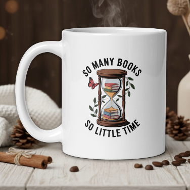 White mug with a design of an hourglass and text 'So many books, so little time' on a wooden table with coffee beans and a vase in the background.