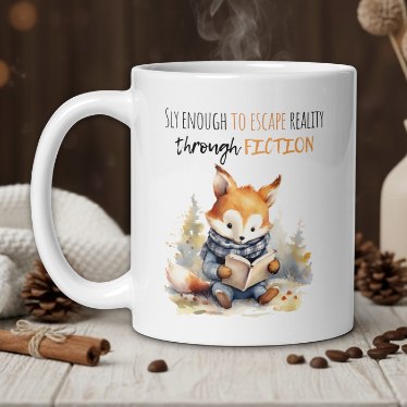 White mug with a fox illustration and text on a wooden table with coffee beans and a vase.