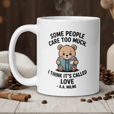 White mug with a teddy bear graphic and humorous quote on a wooden table with decorative items.