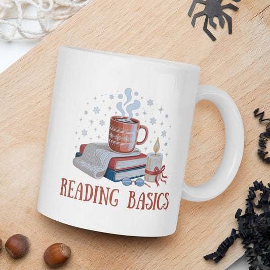 White mug with 'Reading Basics' design on a wooden board with nuts and spider decorations.